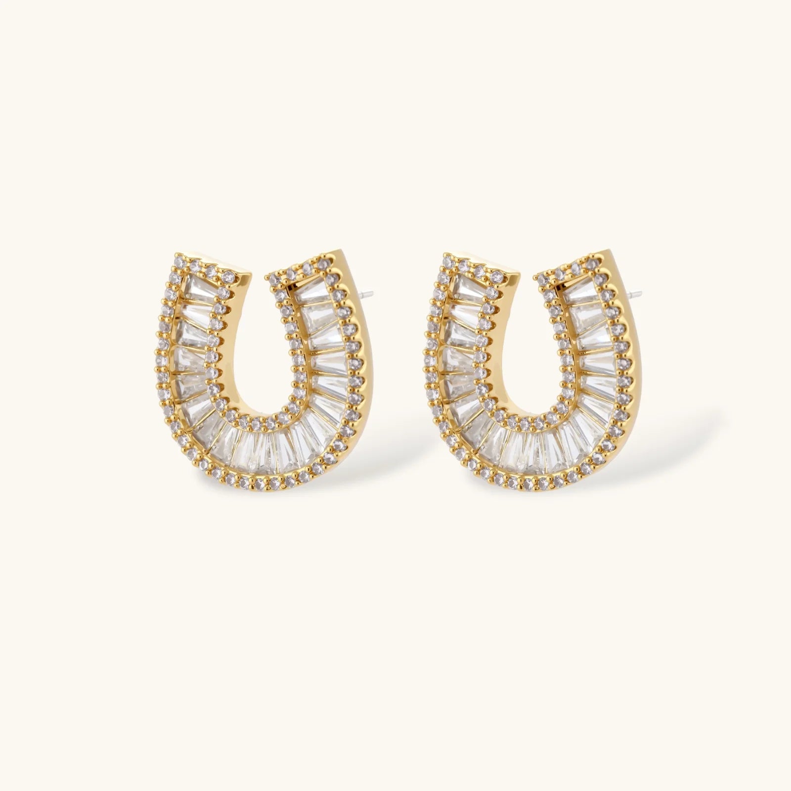 Sparkling horseshoe-shaped jewelry set with AAA cubic zirconia in gold-plated and white gold finishes on cream background.