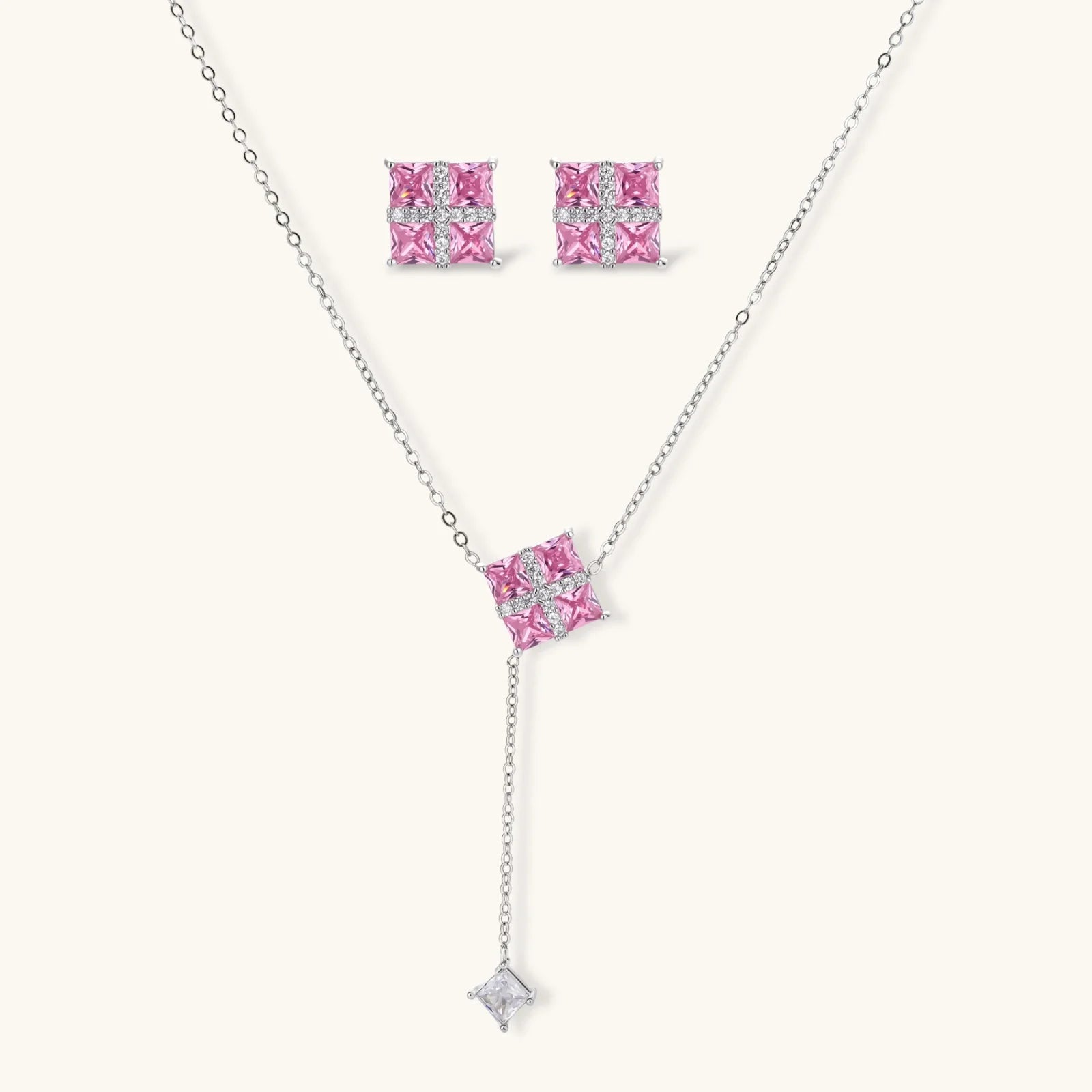 White gold plated jewelry set with pink cubic zirconia stones in geometric cross design, featuring Y-necklace and square stud earrings