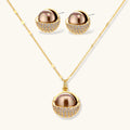 Elegant spherical pendant necklace and earrings set featuring crystal-pavé bottom half in gold or silver finish on white background.