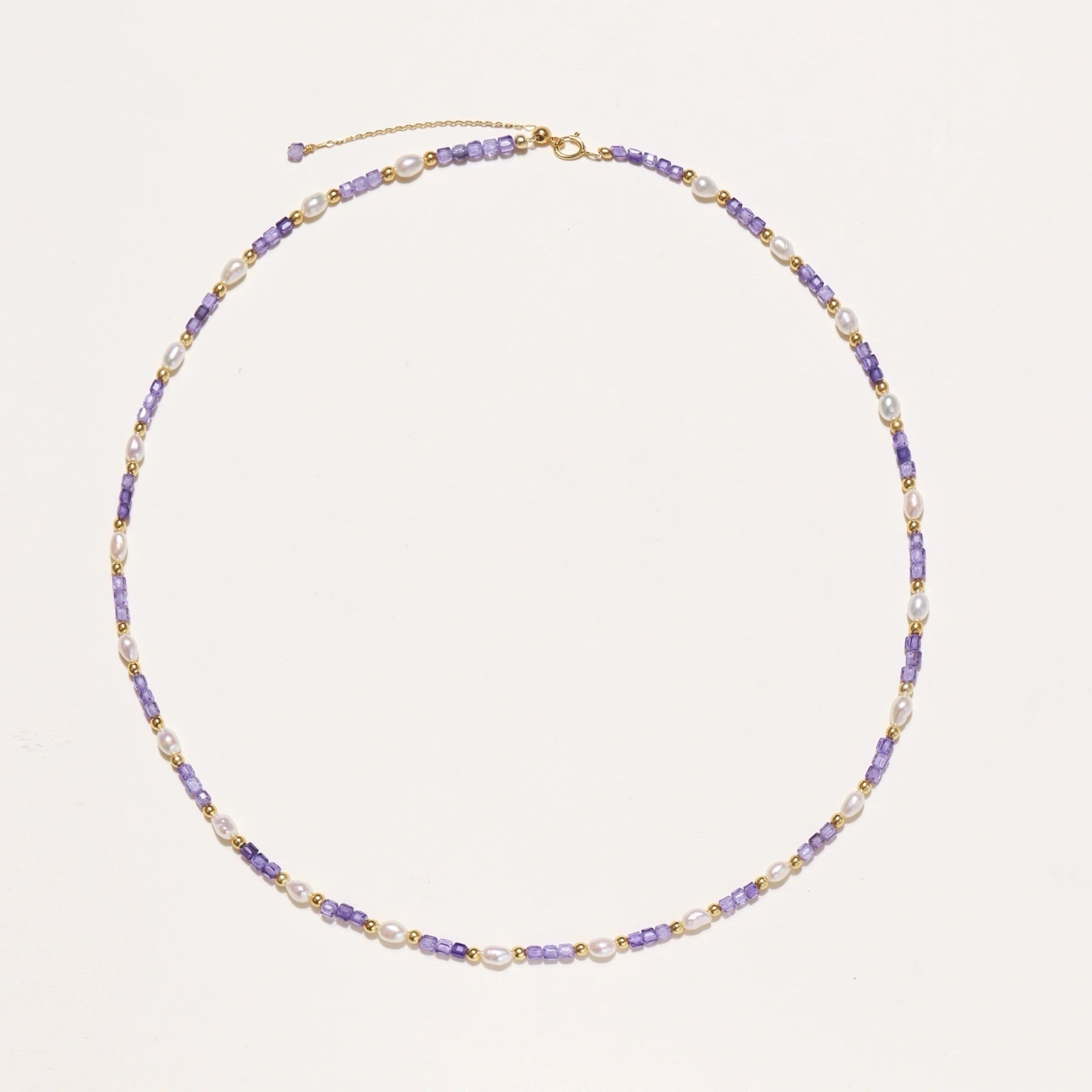 Delicate 18K gold vermeil necklace with alternating lavender zirconia beads and white freshwater pearls on cream background